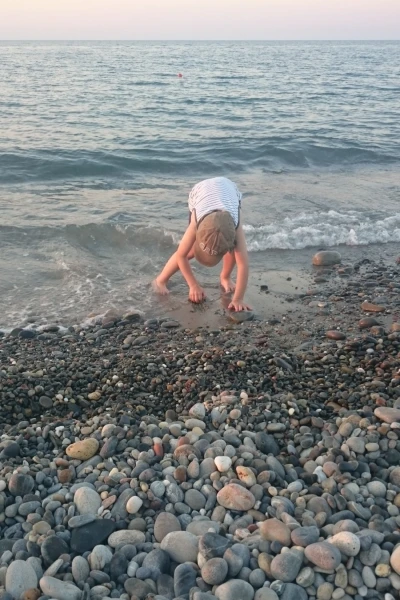Chłopiec bawi się na plaży wśród kamieni